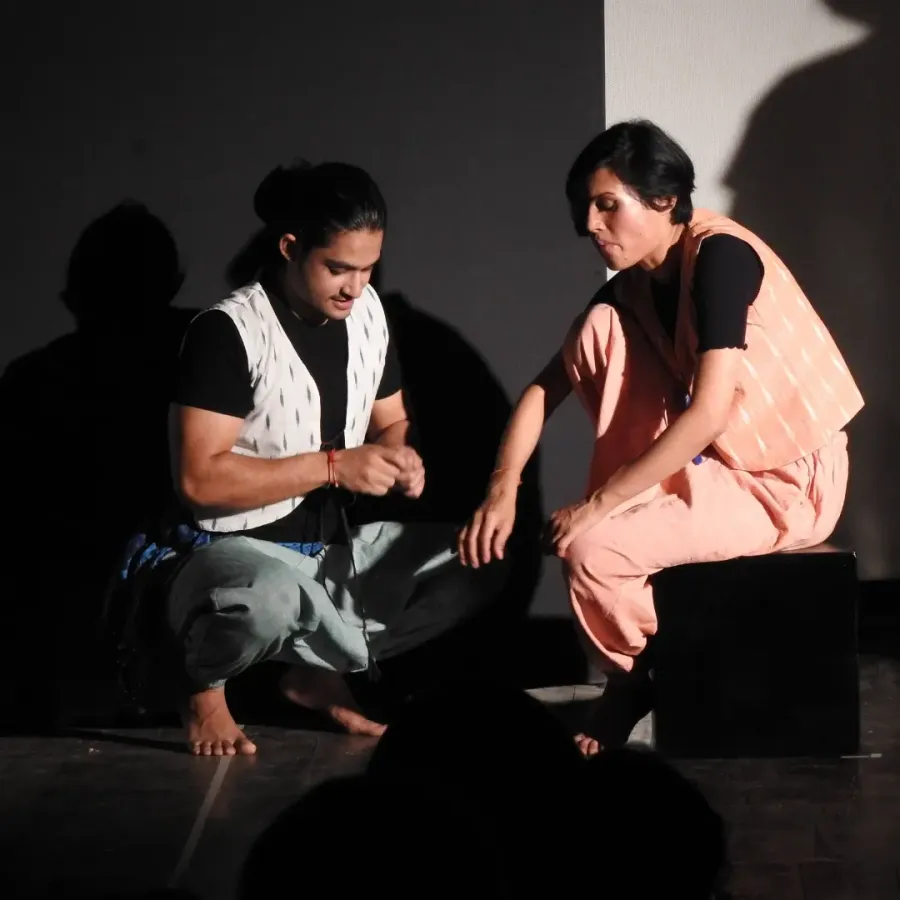I sit with a fellow performer on stage in Beyond the Land of Hattamala