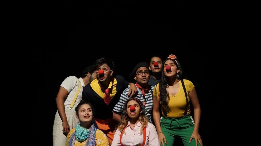 An ensemble in clown costume gathers on stage